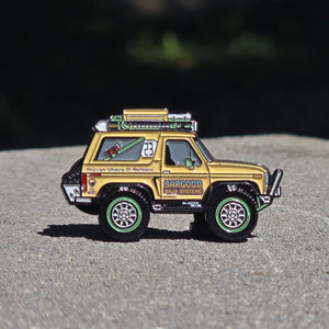 Model of a yellow off-road vehicle on a gray surface with a blurred natural background
