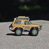 Model of a yellow off-road vehicle on a gray surface with a blurred natural background