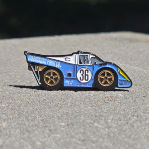 Blue and white race car pin with number 36 on a textured surface